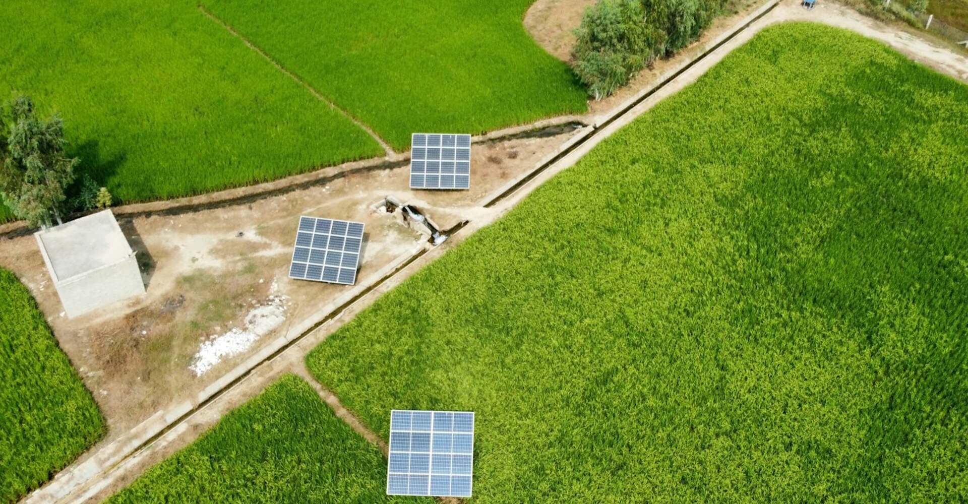 Solar panels beside green farmland seen from above
